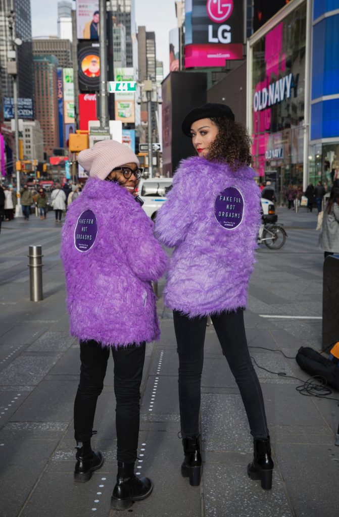 Two women wearing purple fur coats